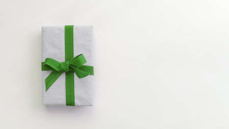 Gift box with gray paper and a green ribbon on a light blue background. Flat lay for father's day concept.の写真素材
