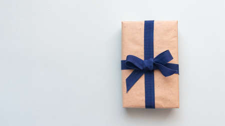 Gift box with kraft paper and a blue ribbon on a light blue background. Flat lay for father's day concept.の写真素材