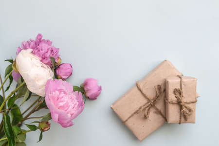 Gift box with kraft paper, peony flowers and a sheet of paper for text on a light blue background. Flat lay for father's day concept.の写真素材