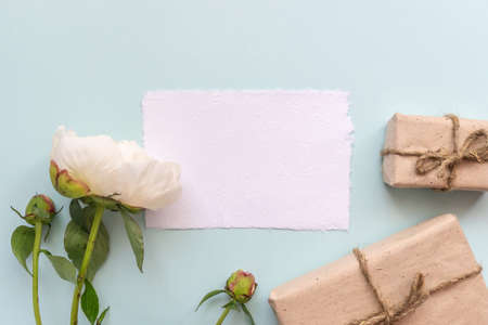 Gift box with kraft paper, peony flowers and a sheet of paper for text on a light blue background. Flat lay for father's day concept.の写真素材