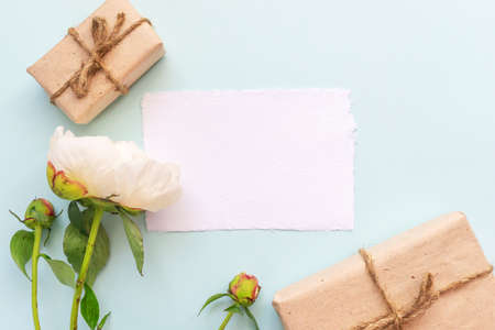 Gift box with kraft paper, peony flowers and a sheet of paper for text on a light blue background. Flat lay for father's day concept.の写真素材