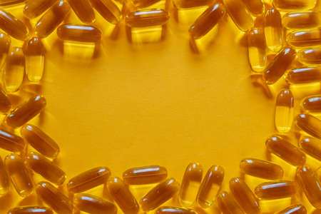 Omega-3 capsules of fish oil on a yellow background.の写真素材