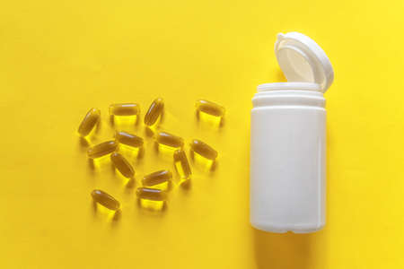 Omega-3 capsules of fish oil on a yellow background.の写真素材