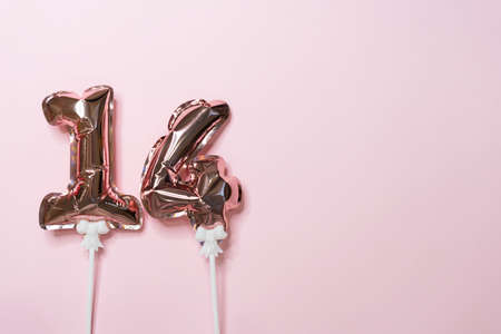 on a pink background, the numbers 14 from the air foil balloonsの写真素材