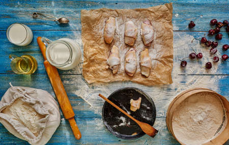 The situation in confectionery, will cook bagels stuffed with cherries, put them on paper for baking, lies next to the flour, milk is in the decanterの写真素材