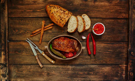 Top view of a housewife in the oven baked beef with vegetables, meat cooked in tomato sauce of garlic and spices, baked in bread with seeds, cutlery lie closeの写真素材