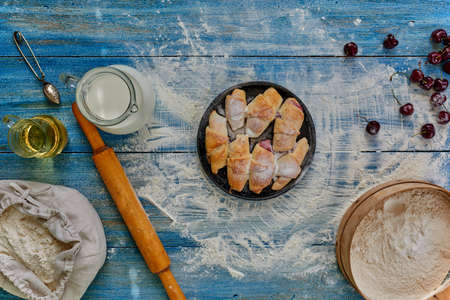 On the vintage wooden table is a round pan on which are laid out bagels with filling sprinkled with powdered sugar, lies near Cherryの写真素材