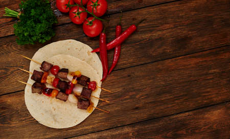 Chef prepared snacks, lamb with vegetables on skewers, fresh tomatoes and greens for saladの写真素材