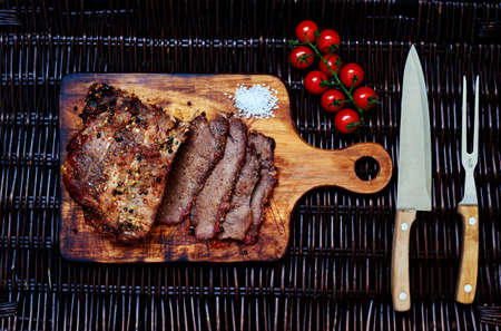 A large piece of pork tenderloin baked in the oven housewife, before serving, cut into portions small steaks, lie next to the tomatoes in the saladの写真素材