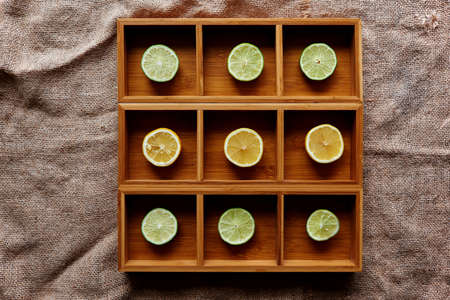 Lemon and lime cut into slices and laid in size in square wooden form with a cell for each lobule