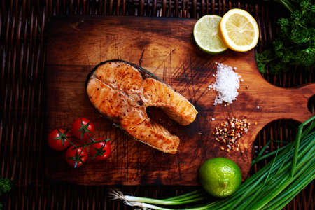 ig salmon steak cooking at home, watered lemon, served it with a salad of fresh tomatoes, Fuming just pulling out of the oven a piece of salmonの写真素材