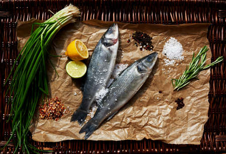 Two small sea bass fish shop on the counter, put them on parchment paperの写真素材
