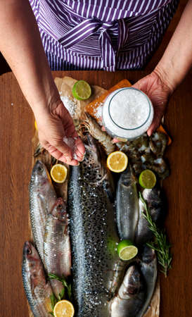 Female hand salted fish and home-cooked marinade, housewife preparing dinner for a large familyの写真素材