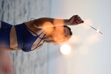 girl holding a sparkler in her hand on the background of the sea