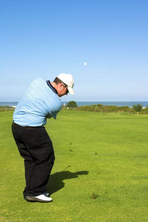 Golfer hitting the ball to the green. Ball in motion in the sky.の写真素材