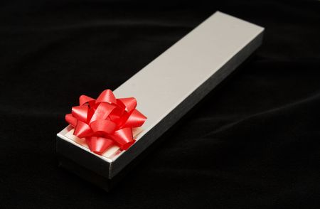 Silver gift box with a pink bow on velvet material background.
