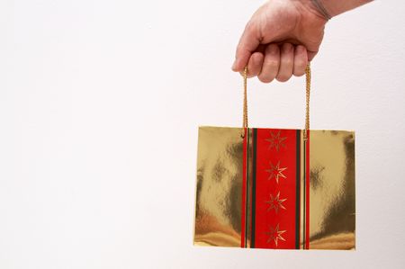 Man's hold holding a gold gift bag next to white background.の写真素材