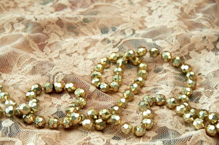 Golden bead necklace on cream lace lingerie.の写真素材