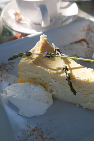 Baked cheesecake served with cream on a square plate and decorated with lavenderの写真素材