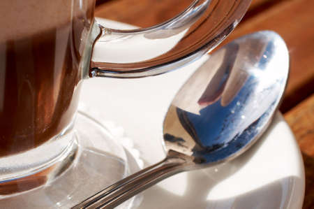 Closeup of cafe latte in tall glass, with a long spoon lying next to it on the saucerの写真素材