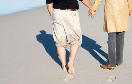 Young couple walking on the beach hand-in-hand, enjoying their winter vacationの写真素材