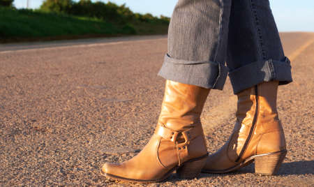 Woman wearing leather boots standing next to the roadの写真素材
