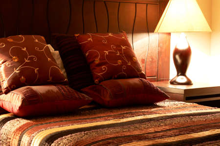Colorful cushions on a bed with a silk bed cover in a guest lodgeの写真素材