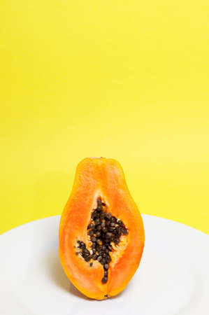 Half of ripe papaya with seeds on yellow backgroundの写真素材