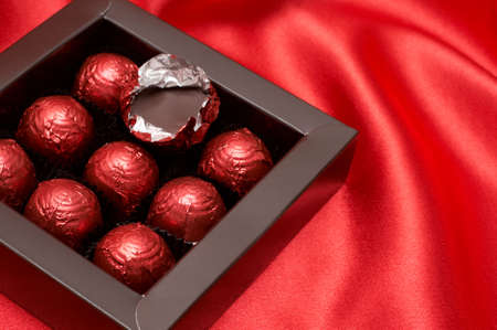 Chocolate Valentines truffles wrapped in red paper on silk material backgroundの写真素材