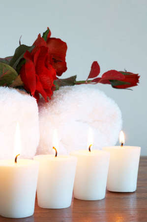 Relaxing spa scene with white fluffy towels, fake roses and burning candlesの写真素材