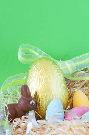 Assortment of chocolate Easter eggs wrapped in colorful paper with bunny in straw