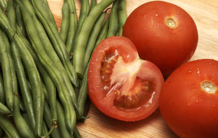 Juicy fresh red tomatoes and green beans on wooden boardの写真素材