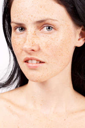 Portrait of a beautiful brunette woman with light grey eyes and freckles on her skinの写真素材