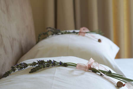 Beautiful bedroom interior with white sheets and flower decorations on pillows. Warm toneの写真素材