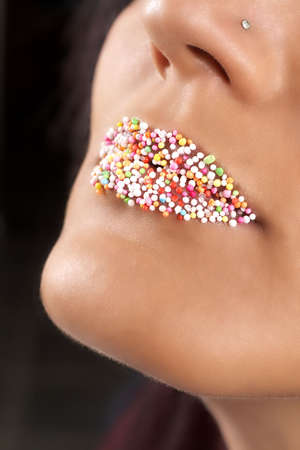 Macro shot of beautiful full lips with bright candy sprinkles. Not a crop. Shallow depth of fieldの写真素材