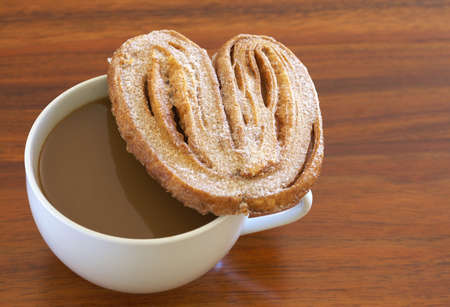 Cup of hot coffee and baked palmier cookie on wooden table backgroundの写真素材