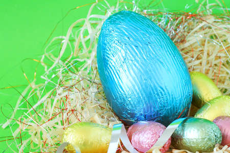 Assortment of chocolate Easter eggs wrapped in colorful paper in strawの写真素材