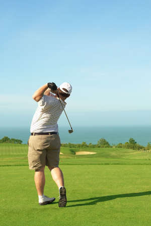 Young male golfer hitting the ball from the green on a beautiful summer dayの写真素材