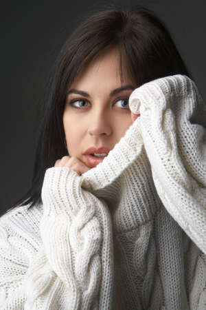 Portrait of a beautiful young brunette woman wearing a white oversized jersey on black backgroundの写真素材