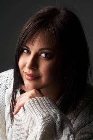 Portrait of a beautiful young brunette woman wearing a white oversized jersey on black background