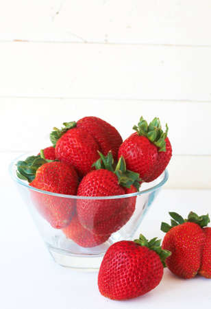 Fresh strawberries in glass bowl against antique white backgroundの写真素材