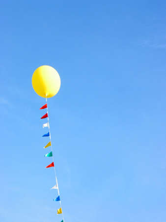 Yellow balloon flying in the blue skyの写真素材