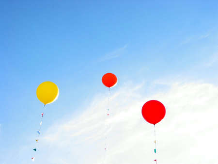 Colorful balloons flying in blue sky on a bright summer dayの写真素材