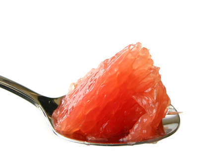 Piece of ruby red grapefruit on a teaspoon isolated on white backgroundの写真素材