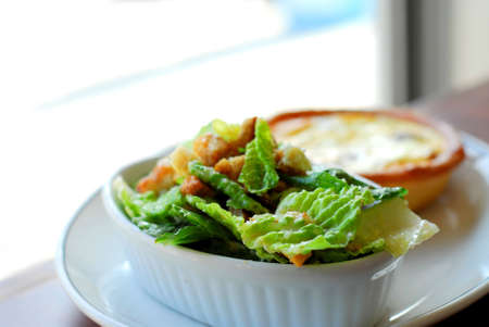 Caesar salad and quiche on white plateの写真素材