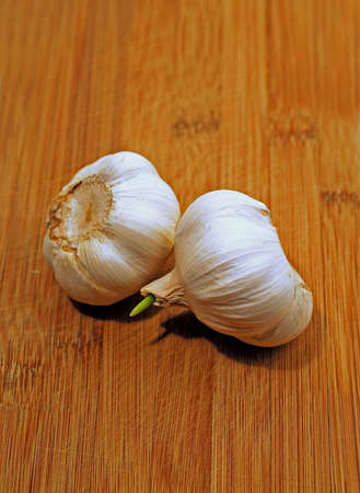 Two garlic bulbs on wooden cutting boardの写真素材
