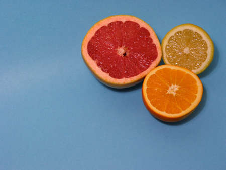 Cut orange, lemon and grapefruit on light blue background with space for copyの写真素材