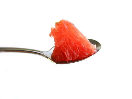 Piece of ruby red grapefruit on a teaspoon isolated on white backgroundの写真素材