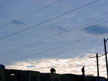 2 construction workers finishing day's work on the top of half build townhome complex, beautiful sunset in the backgroundの写真素材