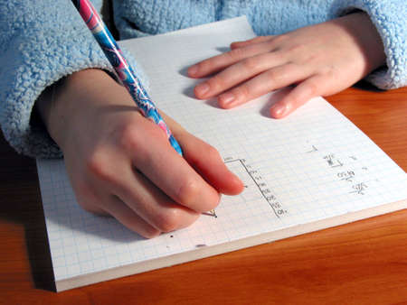 Closeup on the hands of a child doing math homework